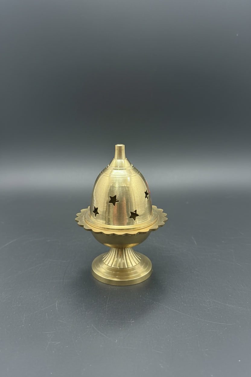 A brass oil lamp with a decorative tiered base and a small blue accent on the top, shown against a plain white background.